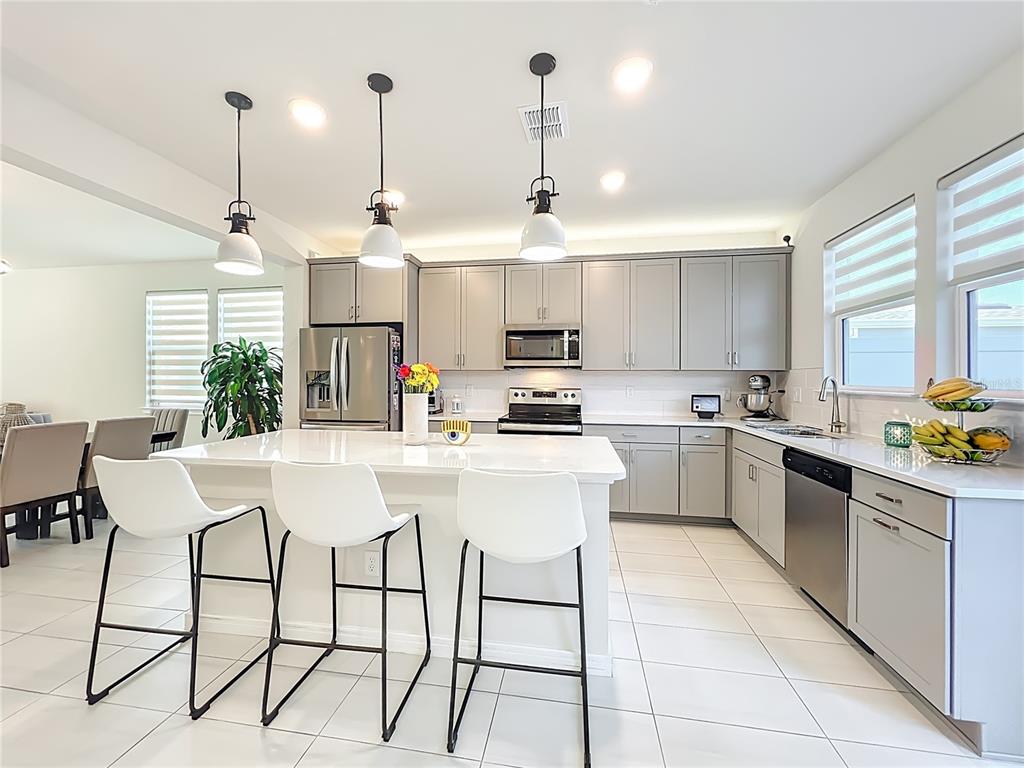 10976 Leafshore Loop Orlando, FL 32829 - Photo 27 of 70 a kitchen with stainless steel appliances kitchen island granite countertop a sink a stove a dining table and chairs
