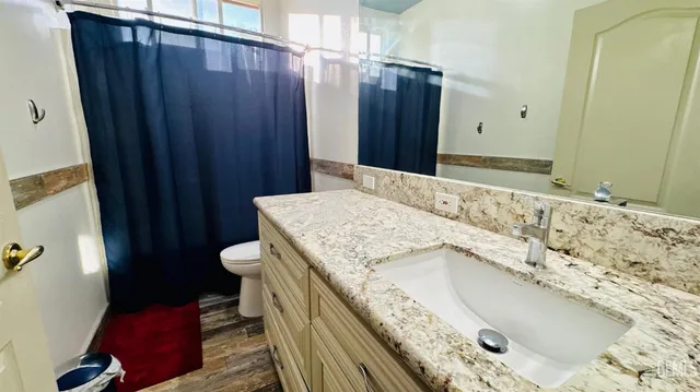 a bathroom with a granite countertop sink and a toilet