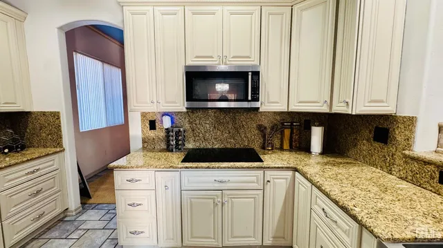 a kitchen with granite countertop a sink a stove and a microwave