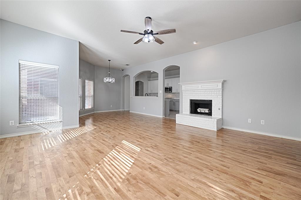 7681 Glasshouse Walk Frisco, TX 75035 - Photo 4 of 28 a view of a livingroom with a fireplace a ceiling fan and wooden floor