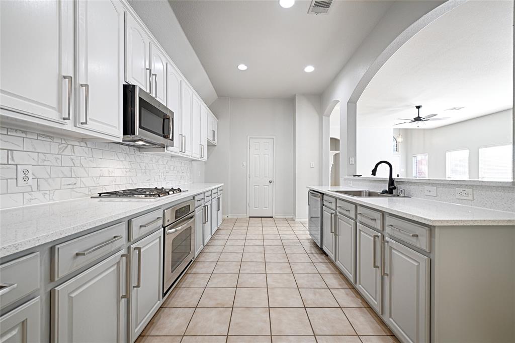 7681 Glasshouse Walk Frisco, TX 75035 - Photo 8 of 28 a open kitchen with stainless steel appliances granite countertop a sink and dishwasher a stove top oven with white cabinets