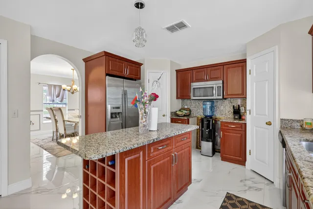 a kitchen with stainless steel appliances granite countertop a kitchen island a stove a sink a dining table and chairs