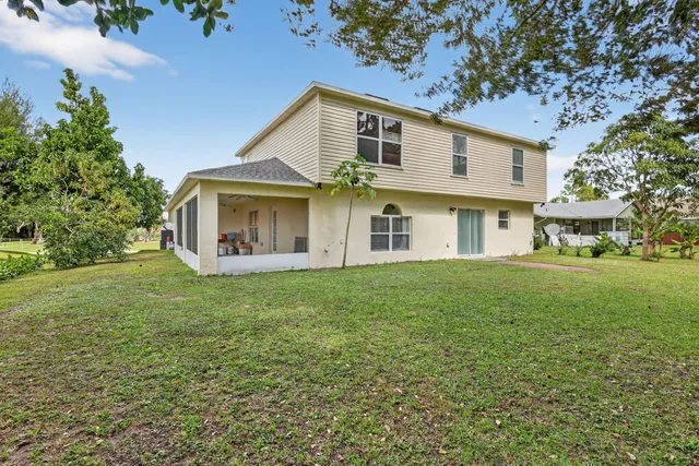 a view of a white house with a big yard and large trees