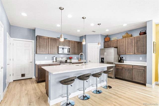 a kitchen with stainless steel appliances granite countertop a sink a stove a refrigerator and island with wooden floor