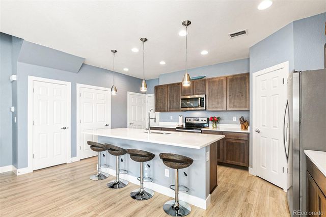 a kitchen with stainless steel appliances a dining table chairs refrigerator sink and cabinets