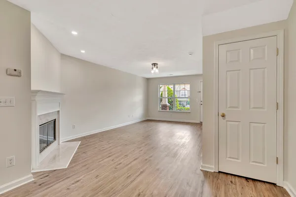 a view of an empty room with window and wooden floor