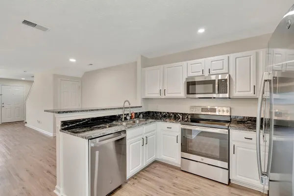 a white kitchen with granite countertop stainless steel appliances