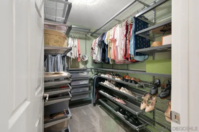 a view of walk in closet with clothes and shoes