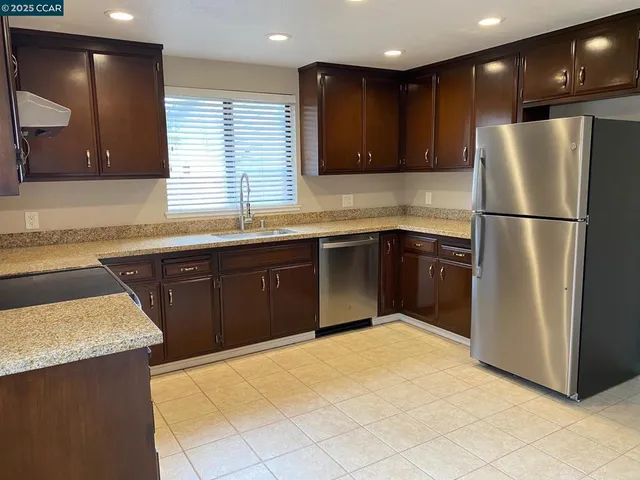 a kitchen with stainless steel appliances granite countertop a sink a refrigerator and a stove top oven