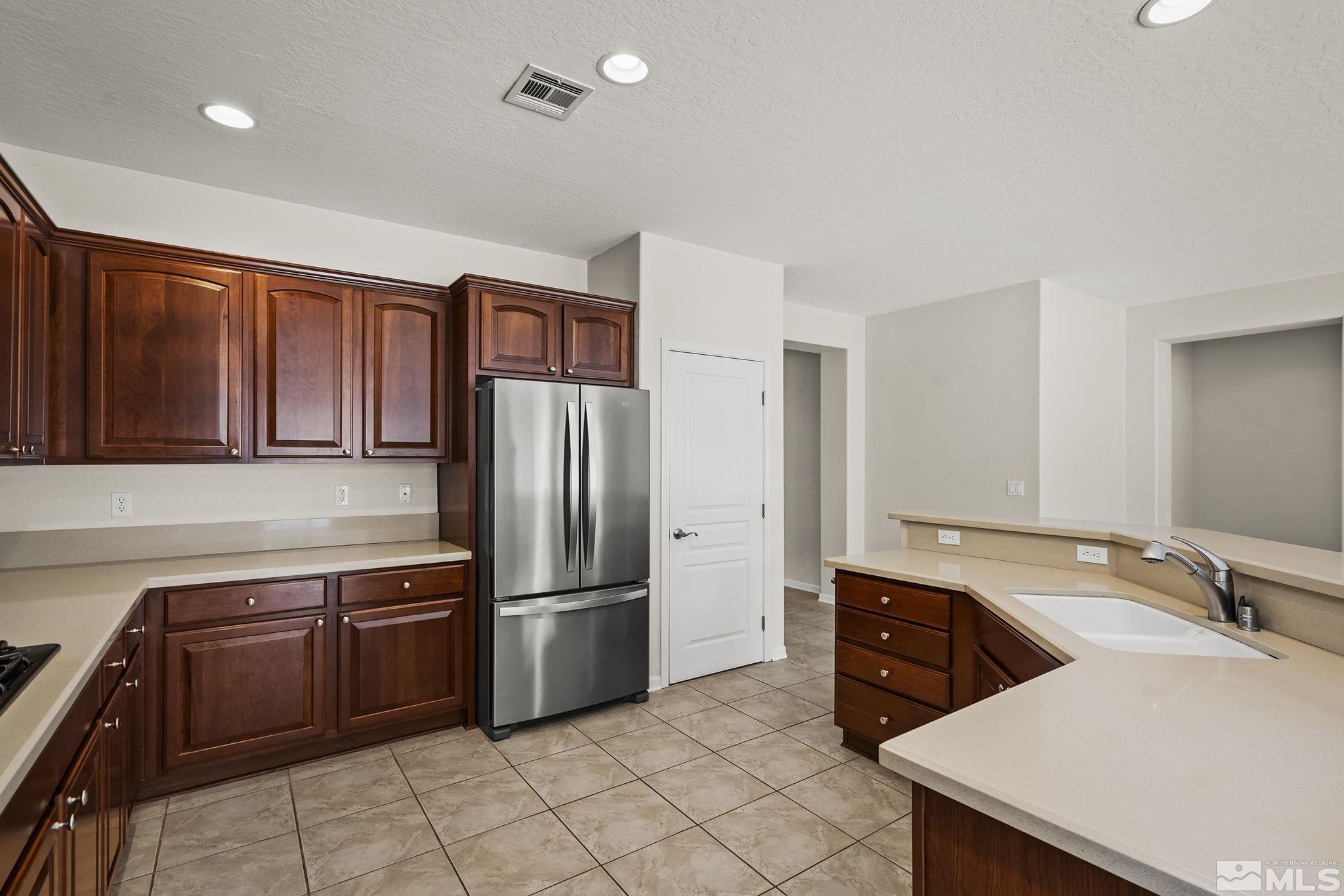 9185 Heritage Ridge Court Reno, NV 89523 - Photo 9 of 31 a kitchen with granite countertop a refrigerator and a stove top oven