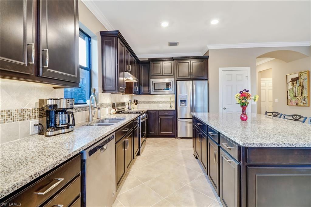 7567 Winding Cypress Drive Naples, FL 34114 - Photo 9 of 24 a kitchen with stainless steel appliances granite countertop a sink refrigerator and cabinets