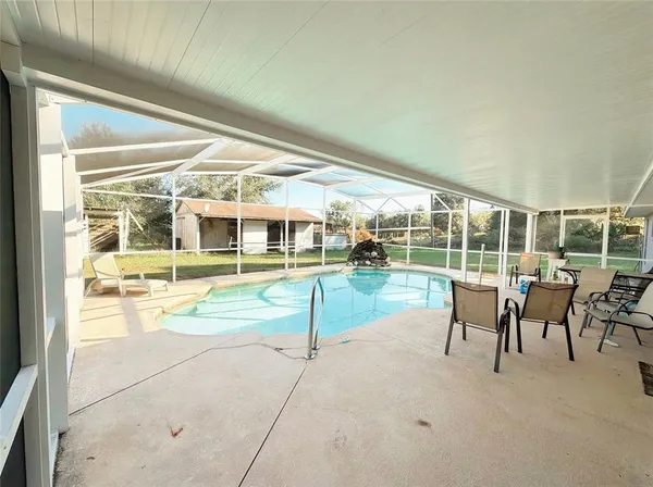 a view of a swimming pool with lawn chairs and floor to ceiling window