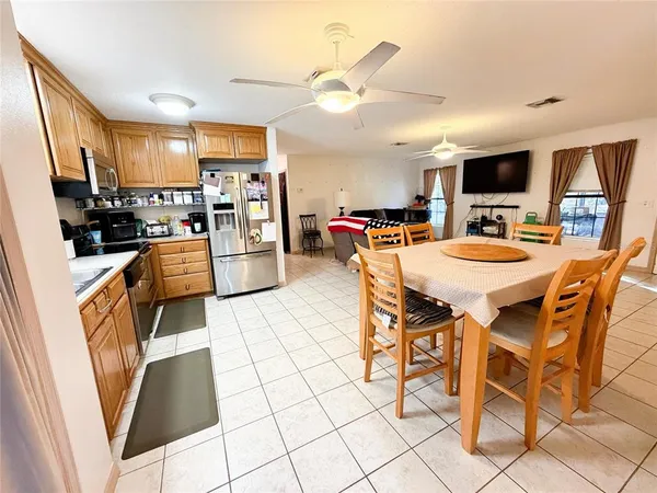 a kitchen with stainless steel appliances kitchen island granite countertop a table chairs and a refrigerator