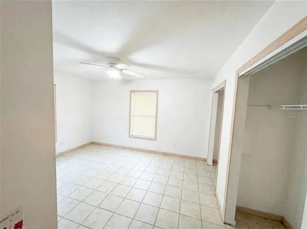 an empty room with windows and fan