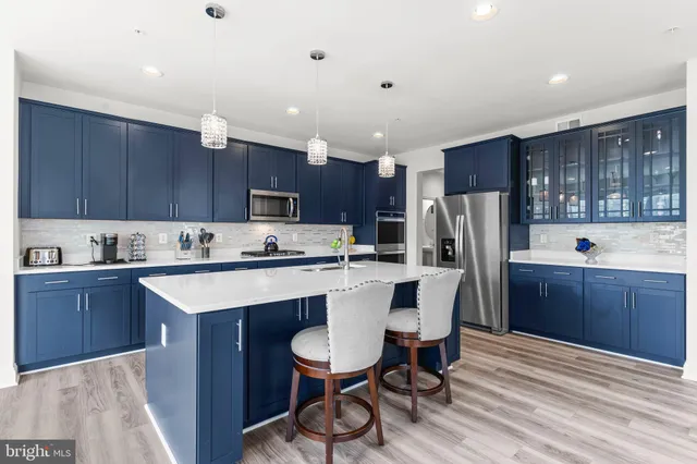 a kitchen with stainless steel appliances granite countertop a sink a stove a dining table and chairs