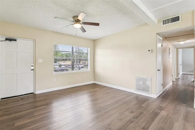 a view of an empty room with wooden floor and a window
