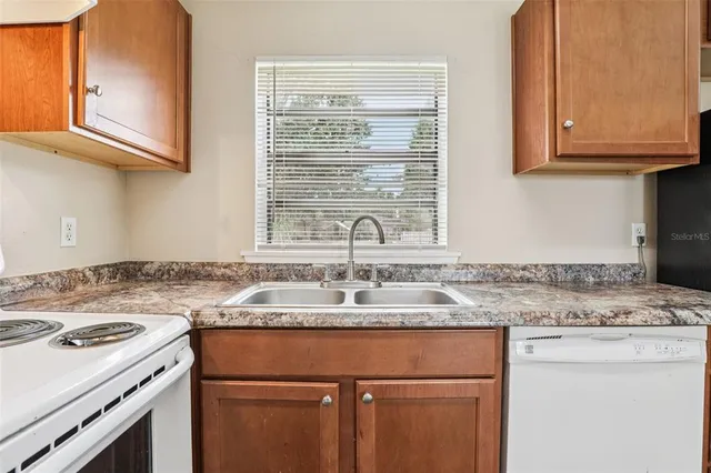 a kitchen with granite countertop a sink stove and cabinets