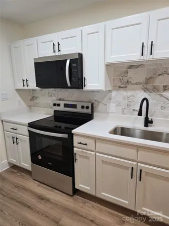 a kitchen with stainless steel appliances a sink a stove and cabinets