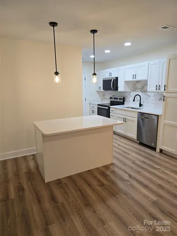 a living room with stainless steel appliances kitchen island granite countertop a sink a stove and white cabinets