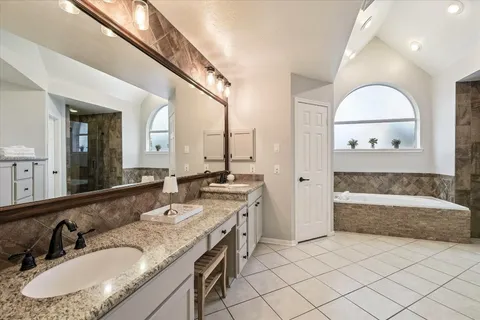 a bathroom with a granite countertop sink mirror and a bathtub