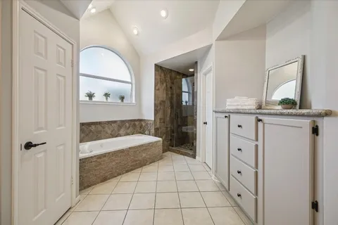 a spacious bathroom with a granite countertop sink a mirror and a bathtub