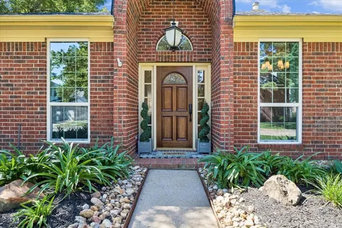 a view of a brick house with plants and large windows