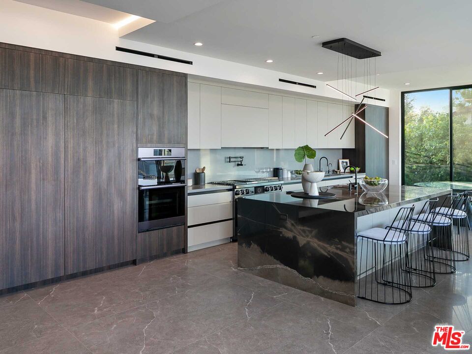 1324 Stradella Road Los Angeles, CA 90077 - Photo 5 of 26 a kitchen with kitchen island granite countertop a sink counter top space appliances and a view of living room
