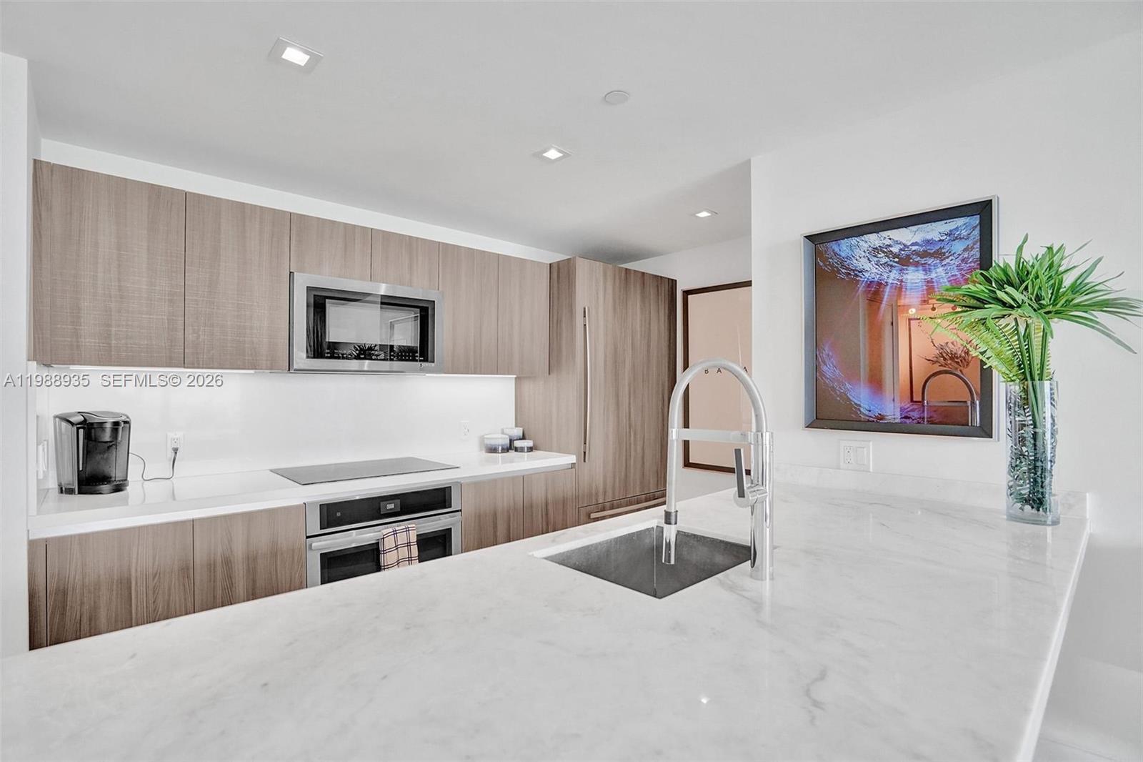 401 North Birch Road, Unit 513 Fort Lauderdale, FL 33304 - Photo 21 of 37 a kitchen with stainless steel appliances kitchen island granite countertop a sink a stove a microwave a counter top space and cabinets