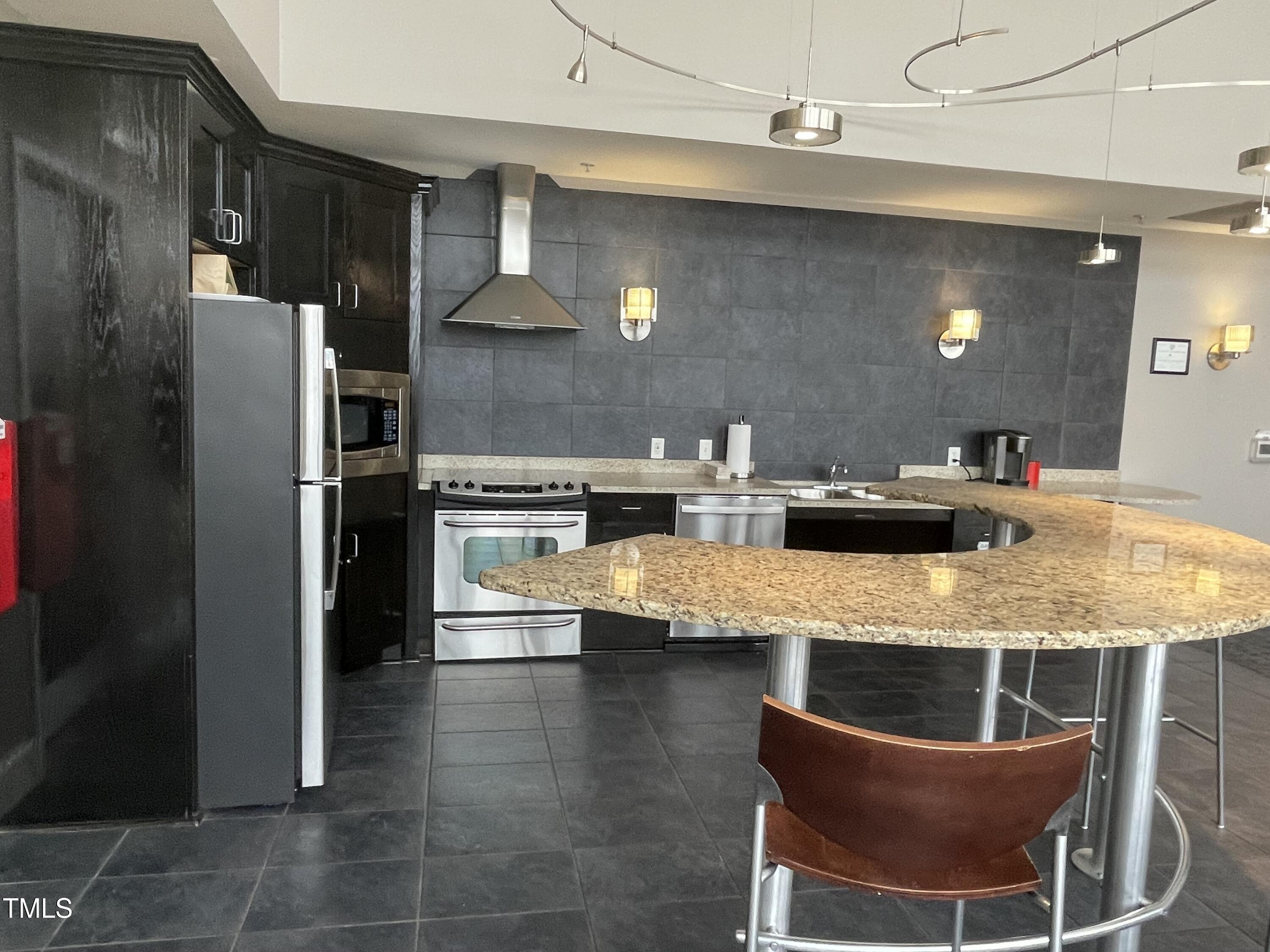 400 West North Street, Unit 604 Raleigh, NC 27603 - Photo 33 of 46 a kitchen with kitchen island a counter top space a sink stainless steel appliances and cabinets