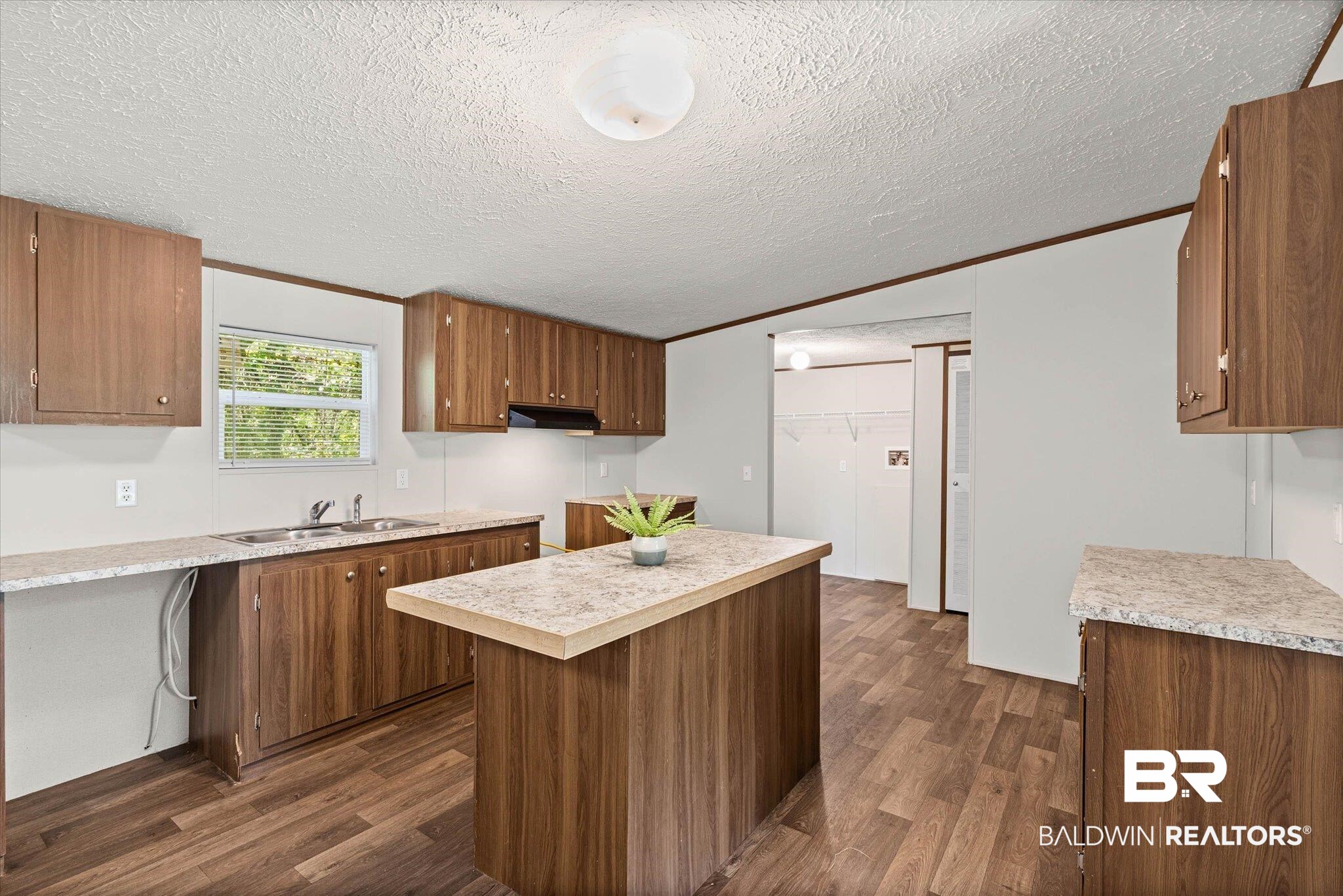 25366 Pollard Road Daphne, AL 36526 - Photo 7 of 22 Kitchen featuring wood-finish cabinetry, light-toned countertops, and wood-finish flooring