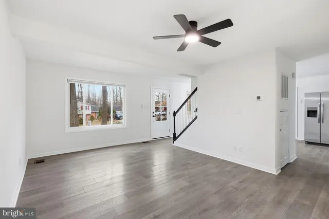 a view of a kitchen with stainless steel appliances granite countertop a dishwasher a stove a refrigerator and white cabinets with wooden floor