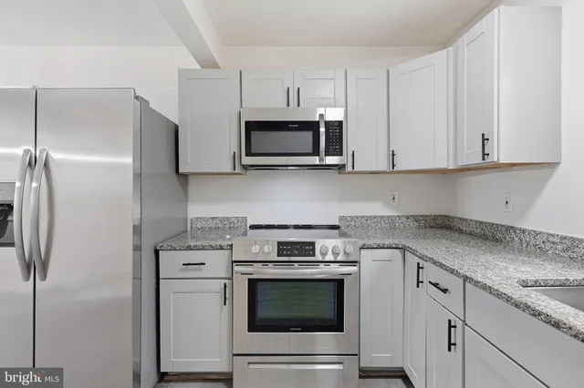 a kitchen with granite countertop white cabinets and a stove