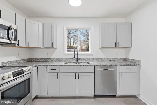 a kitchen with granite countertop white cabinets and stainless steel appliances