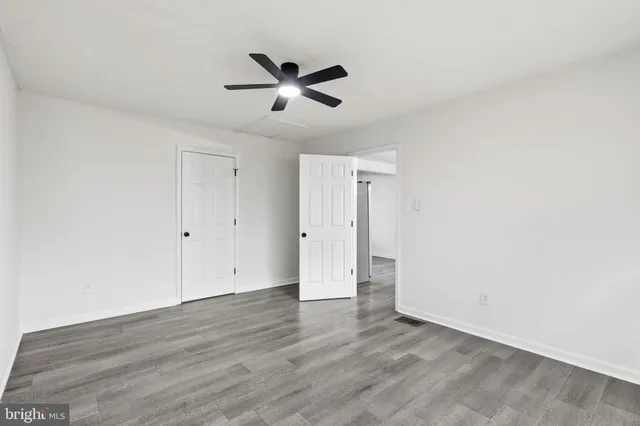 an empty room with wooden floor ceiling fan and windows