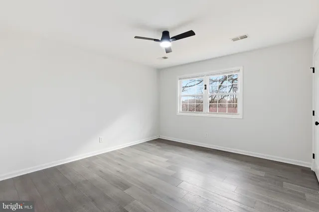 an empty room with a window and ceiling fan