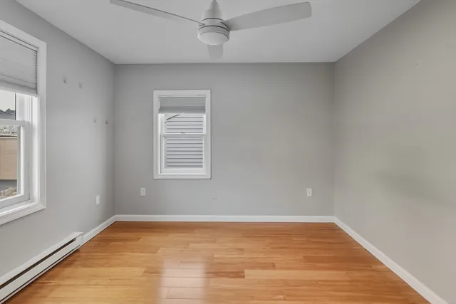 a view of empty room with wooden floor and fan