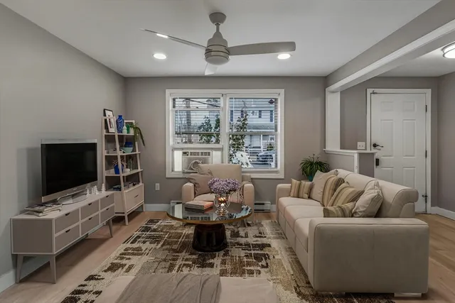 a living room with furniture a flat screen tv and a window