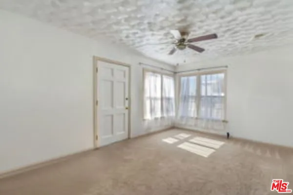 an empty room with windows and chandelier fan