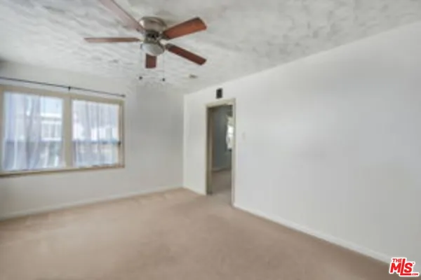 an empty room with a window and a ceiling fan