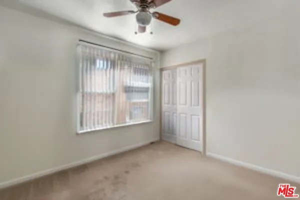 an empty room with chandelier fan and windows