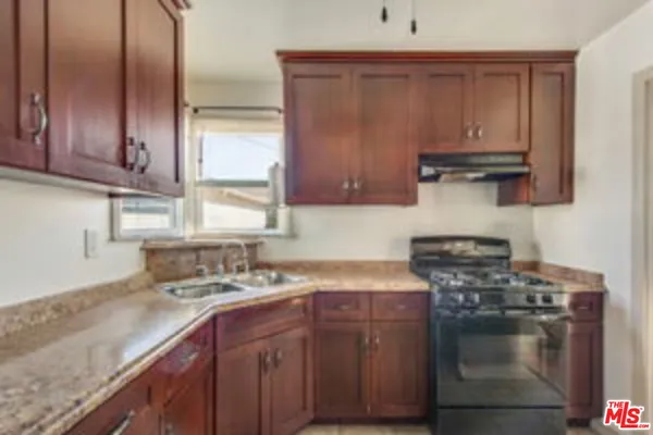a kitchen with stainless steel appliances granite countertop a sink stove and cabinets