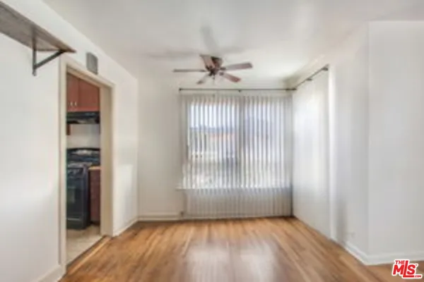 an empty room with wooden floor chandelier and windows