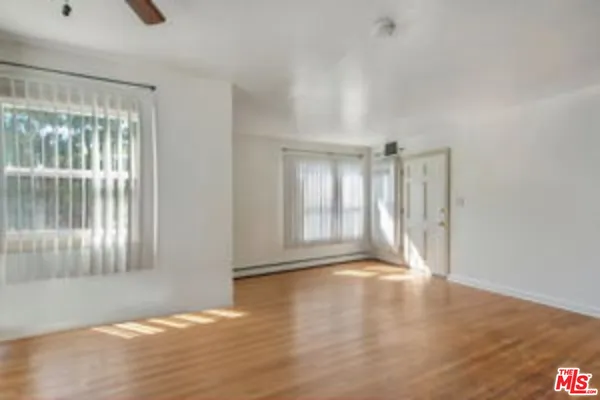a view of an empty room with wooden floor and a window