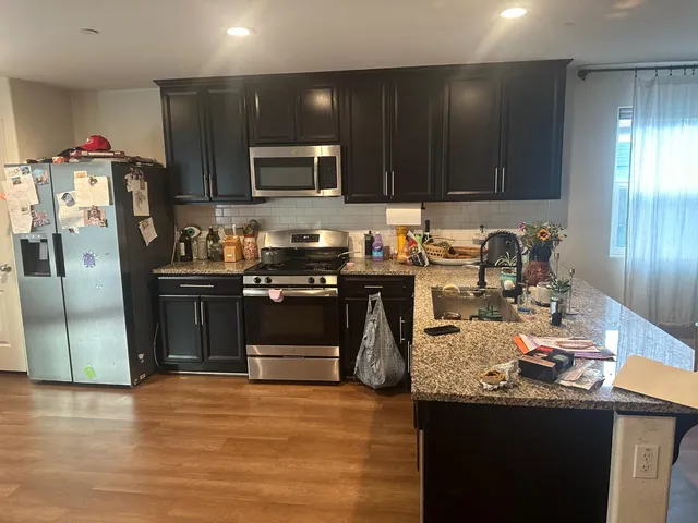 a kitchen with stainless steel appliances granite countertop a sink stove and refrigerator