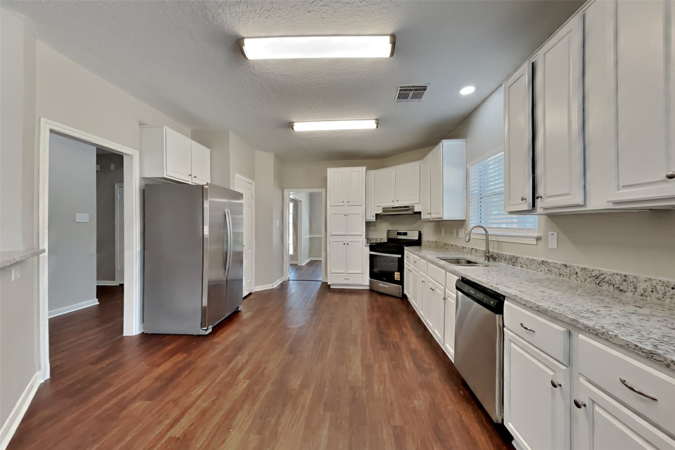 8615 Mile Run Road Humble, TX 77346 - Photo 3 of 19 a kitchen with stainless steel appliances granite countertop a refrigerator a stove top oven a sink and dishwasher with wooden floor