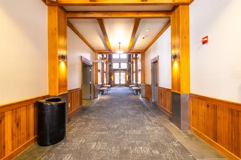 a view of a hallway with wooden floor and windows