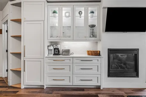 a living room with furniture a flat screen tv and a refrigerator