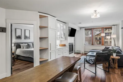 a living room with furniture a flat screen tv and a refrigerator