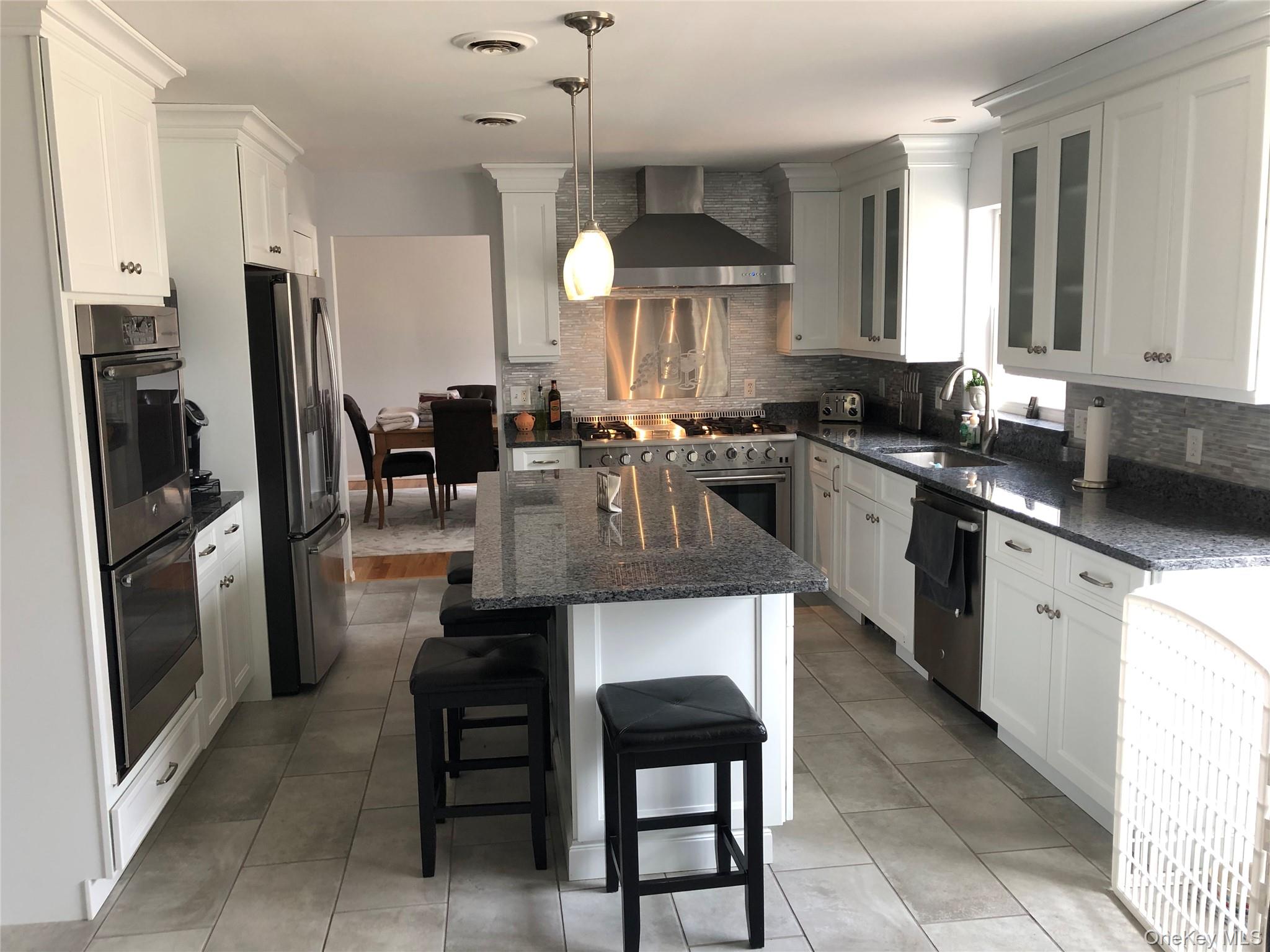 95 Weed Road Pine Bush, NY 12566 - Photo 4 of 31 Kitchen featuring an island with seating, white shaker cabinetry, stainless steel appliances, granite countertops, and a tiled backsplash