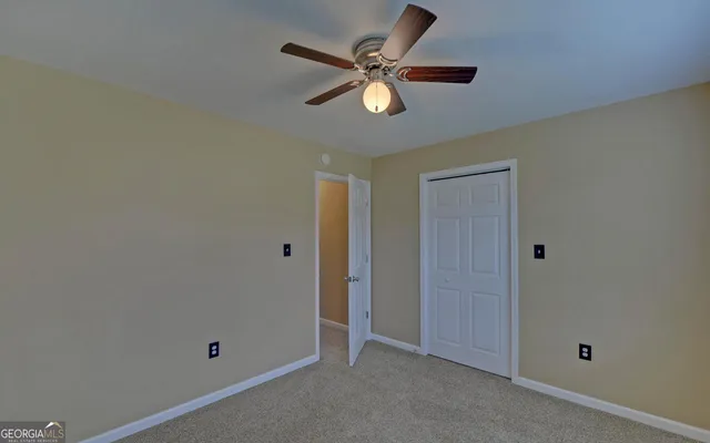 an empty room to ceiling fan and window